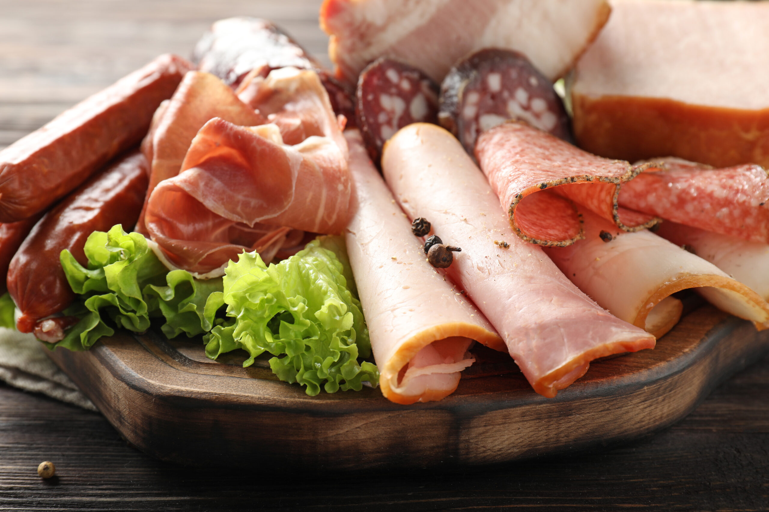 Wooden board with assortment of delicious deli meats on wooden board